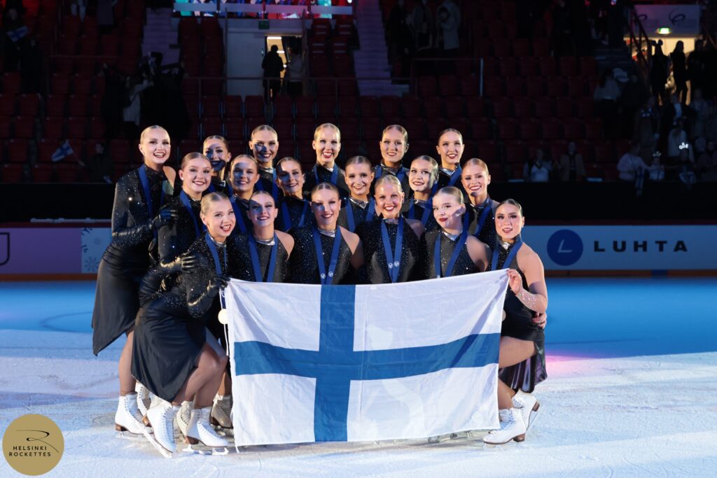 Vuoden 2025 maailmanmestarijoukkue Helsin Rockettes ja Suomen lippu
